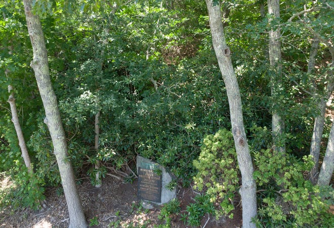 A stone that commemorates a tribal burying ground and meeting house sits on a thickly wooded hill off Scenic Highway in Bourne.